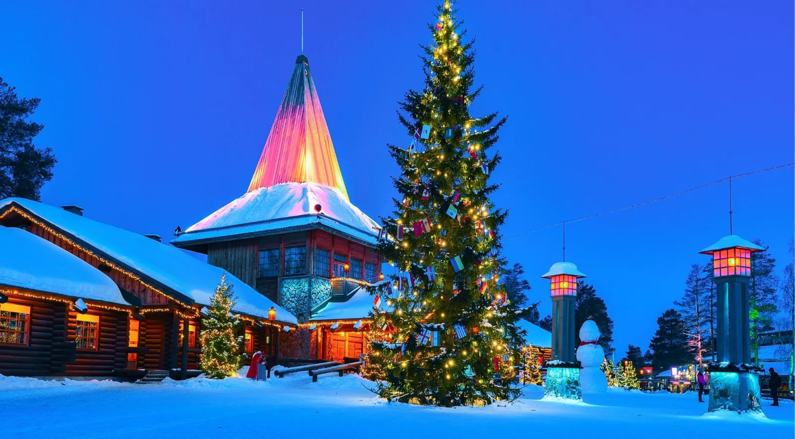 Santa Claus Village lit up at blue hour with a glowing Christmas tree