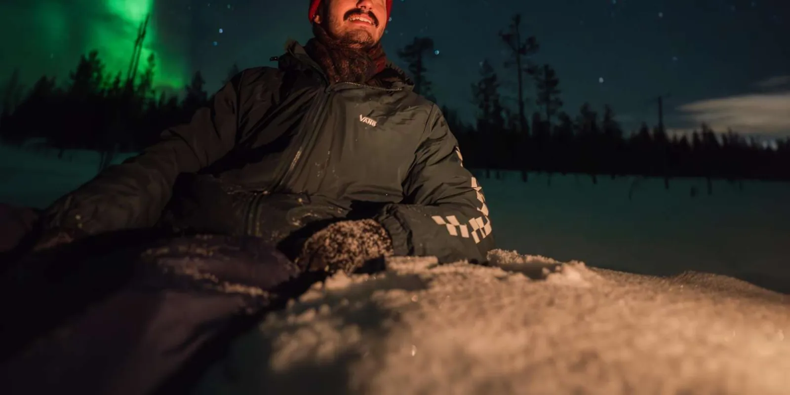 Traveler watching the aurora glow above the Arctic forest near Rovaniemi