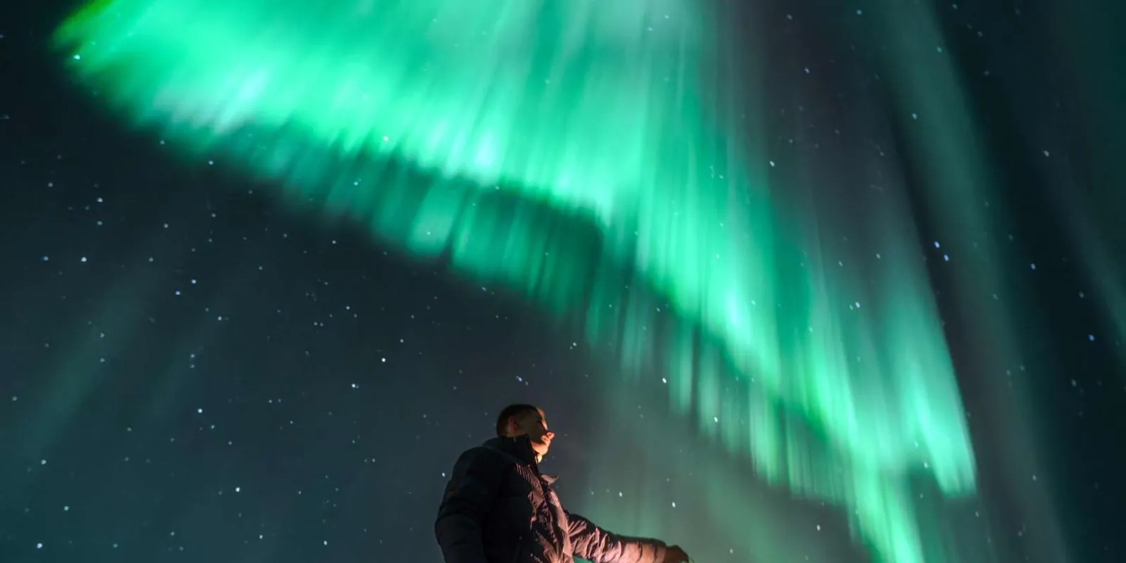 Guide-captured photo of guests standing under the Northern Lights