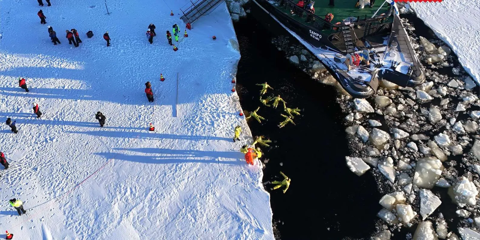 Guests ice floating in orange survival suits in the frozen sea