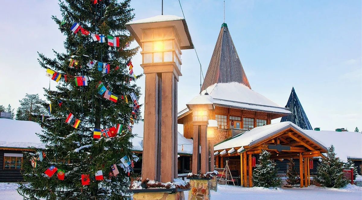 Snowy entrance to Santa Claus Village with an international-flag Christmas tree on the Arctic Circle in Rovaniemi